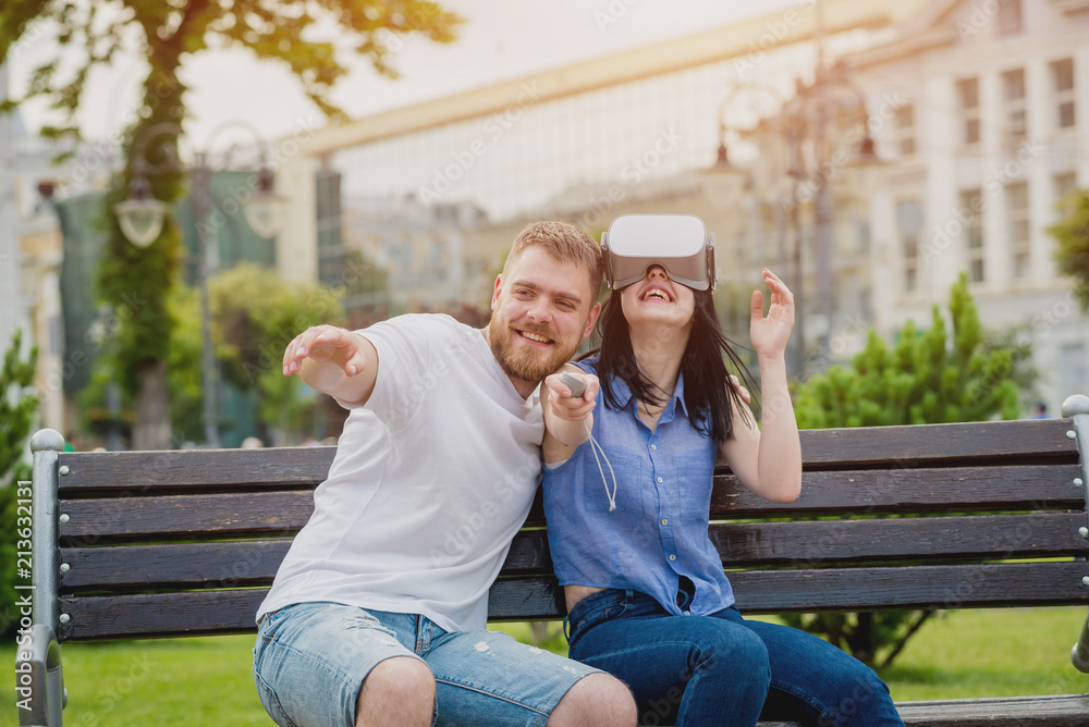 A young couple plays a game using virtual reality glasses on the street. A young couple plays a game using virtual reality glasses on the street.