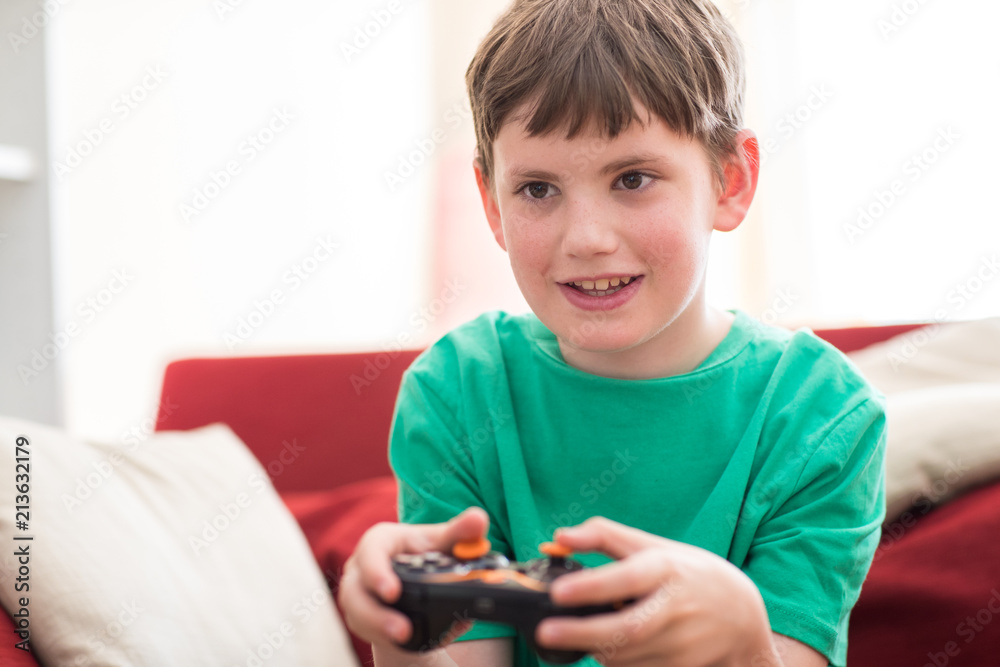 Boy Sitting On Sofa At Home Playing Computer Game Boy Sitting On Sofa At Home Playing Computer Game
