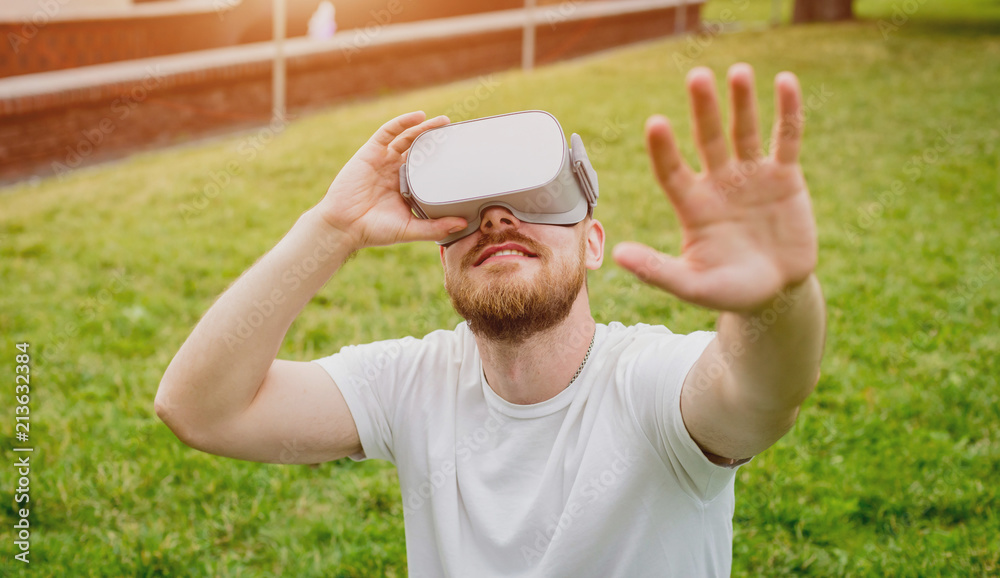 A young man plays a game wearing virtual reality glasses on the street. A young man plays a game wearing virtual reality glasses on the street.