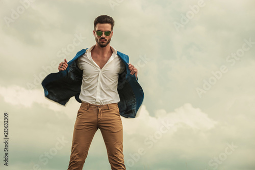 seductive man wearing sunglasses and suit standing in wind photo