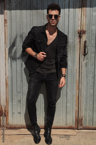 handsome man in black clothes standing outside near garage door © Viorel Sima