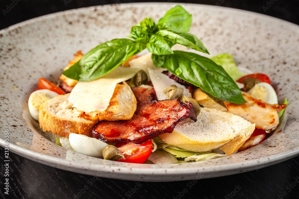 Italian Cuisine. Classic Caesar salad with chicken, cherry tomatoes, mix salad, parmesan cheese, bread croutons, rusks and basil. The concept is a beautiful serve in the restaurant. Copy space