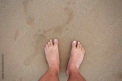 men's feet on the sand