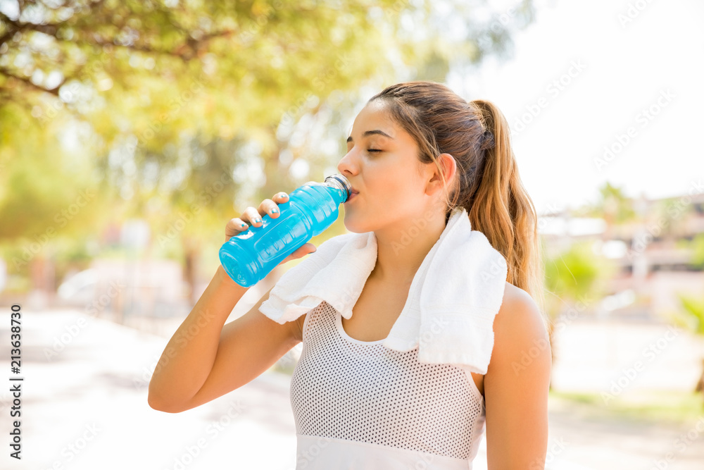 Woman drinking water after running workout Woman drinking water after running workout