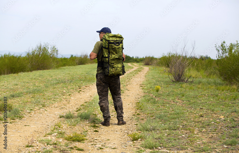 A traveler is walking along the road with a backpack