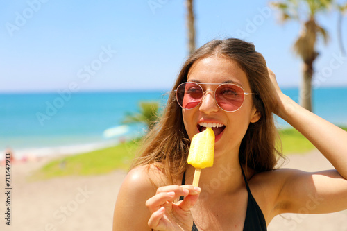 Beautiful girl with sunglasses eating popsicle on Malaga beach in her travel holidays in Southern Spain