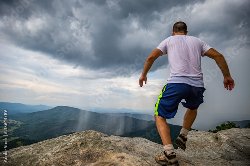 Man Running Towards the edge of  McAfee Knob edge above scenic stormy Valley. photo