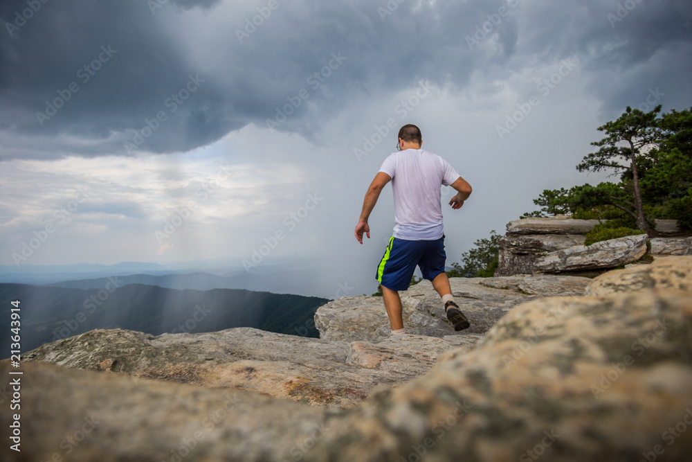 Man Running across McAfee Knob while raining in the valley