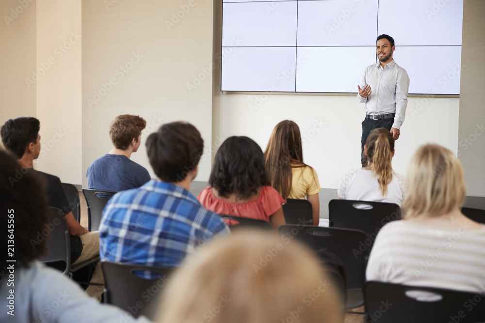 Teacher Giving Presentation To High School Class In Front Of Screen