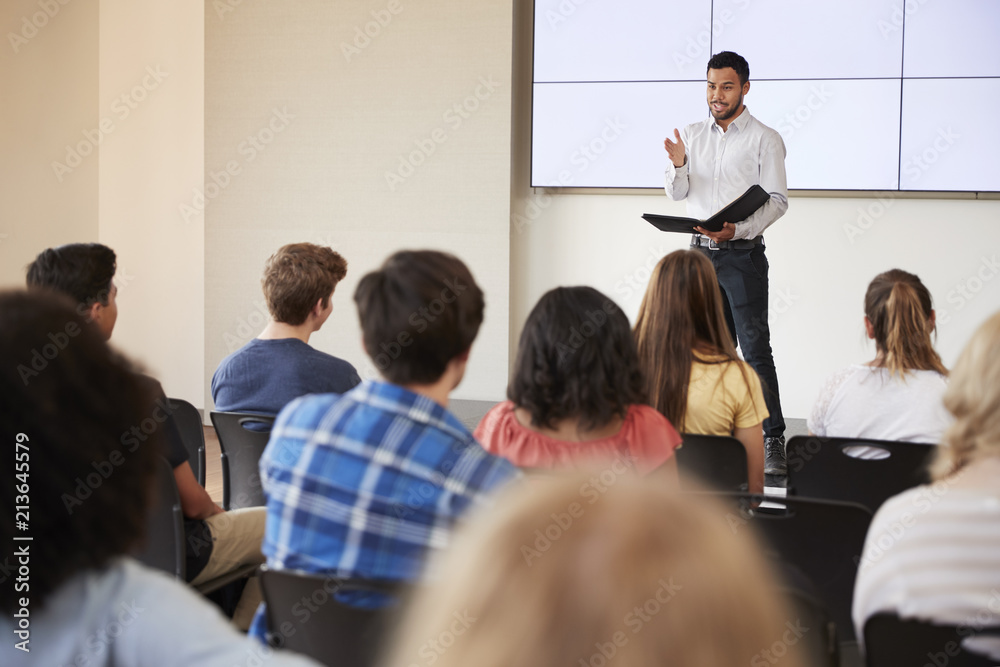 Teacher Giving Presentation To High School Class In Front Of Screen Teacher Giving Presentation To High School Class In Front Of Screen
