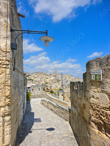 narrow street in ancient town of Matera (Sassi di Matera), European Capital of Culture 2019,and UNESCO Heritage  site  with city view and blue sky and clouds, Basilicata, southern Italy              