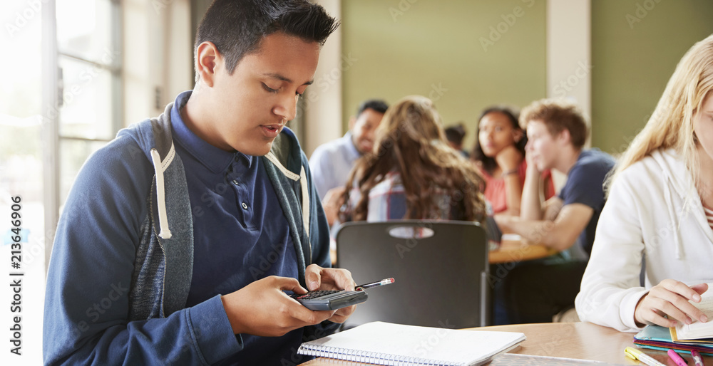 Male High School Student With Calculator Working At Desk Male High School Student With Calculator Working At Desk