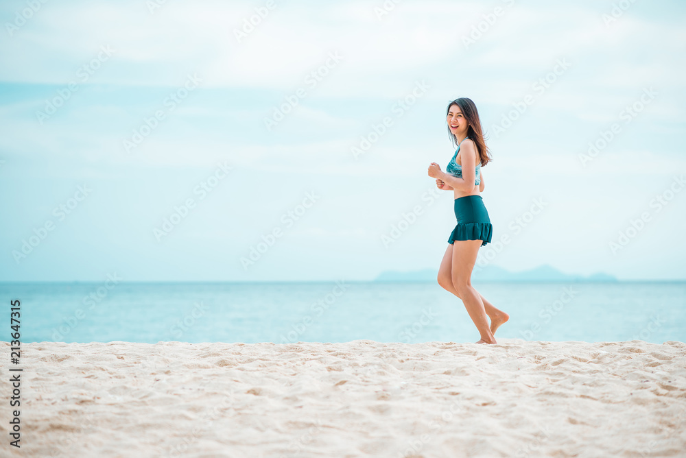 Happy Asian woman jogging on the beach in the morning