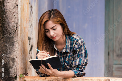 young charming female is writing something in her diary.