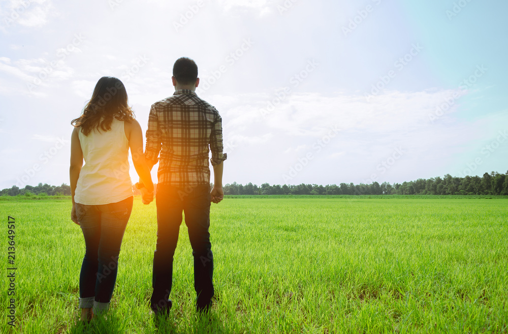 pretty woman and her boyfriend in the meadow with sunlight. Filtered image.