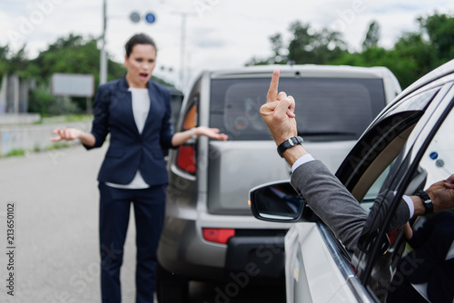 cropped image of driver showing middle finger to businesswoman on road © LIGHTFIELD STUDIOS