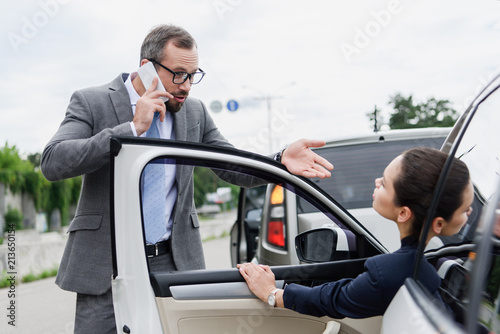 businesspeople quarreling on road after car accident, man talking by smartphone © LIGHTFIELD STUDIOS