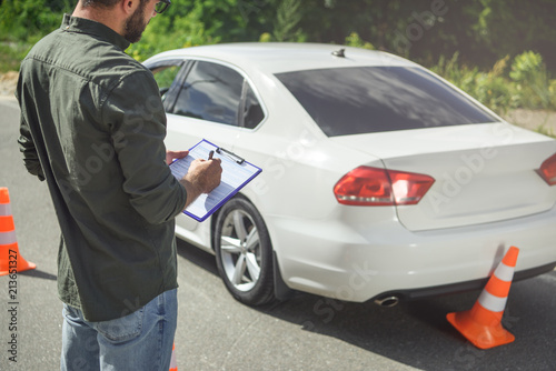 cropped image of man writing something to car insurance on road © LIGHTFIELD STUDIOS