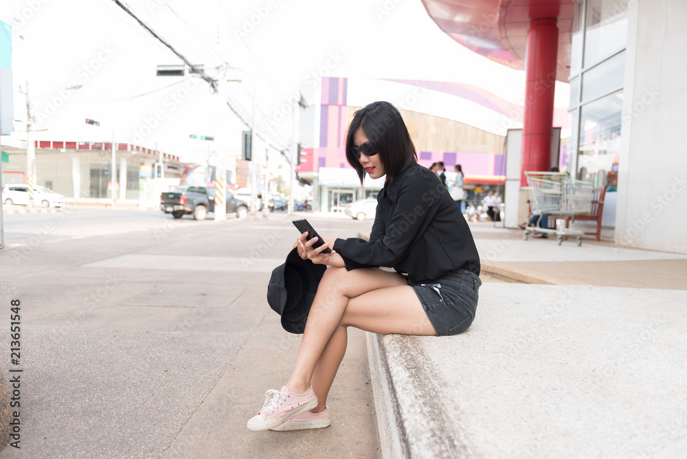 Portrait young hipster woman in black dress using mobile phone at public.