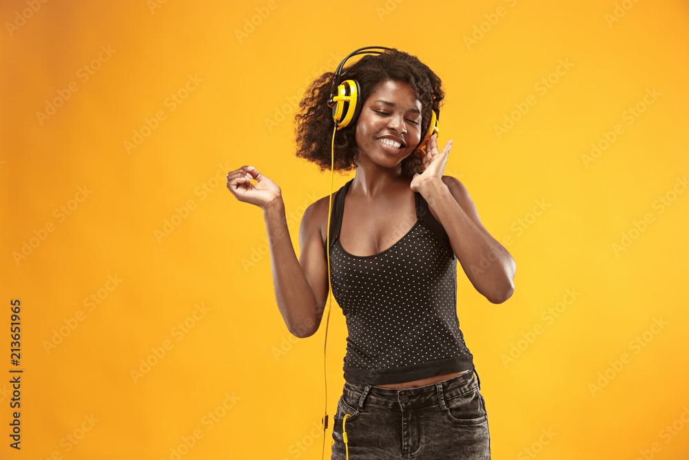 Studio portrait of adorable curly girl happy smiling during photoshoot. Stunning african woman with light-brown skin relaxing in headphones Studio portrait of adorable curly girl happy smiling during photoshoot. Stunning african woman with light-brown skin relaxing in headphones