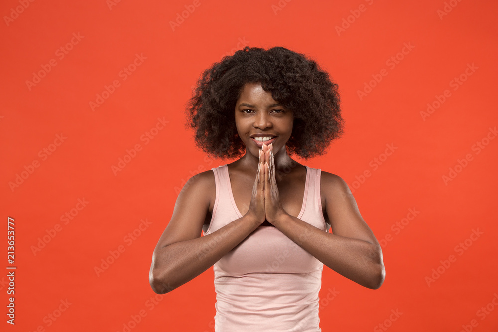 The happy african woman standing and smiling against red background.