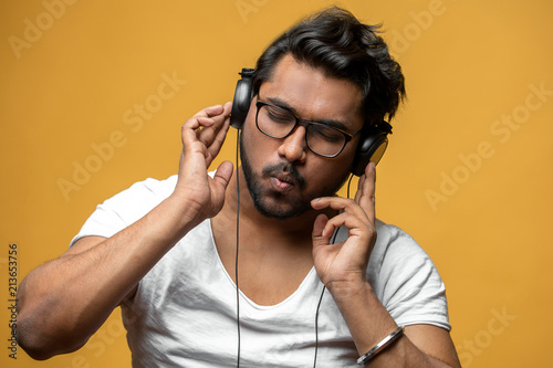 Hindoo young man is mad at music isolated on the yellow background. music taste. put out song. hipster spending time on music photo