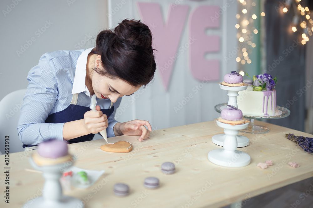 confectioner in a blue apron on a light background with a cake confectioner in a blue apron on a light background with a cake