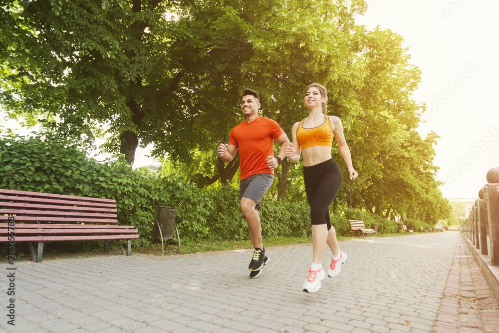 Athletic couple running together in park