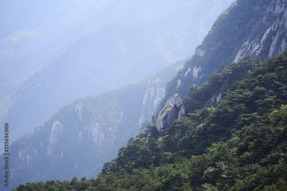 July 2018, Lushan National Park, China. Landscape photo, mountain tops, crop view. A single rock stood out among the mountain range with other mountain as background.