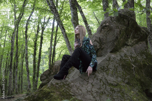 Fashion Model Girl on the Rock in the green summer forest