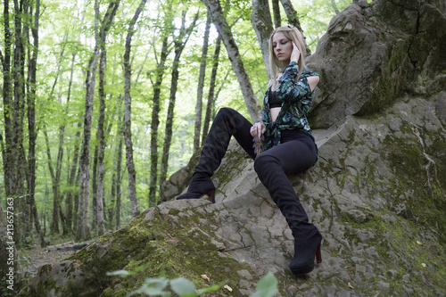 Fashion Model Girl on the Rock in the green summer forest