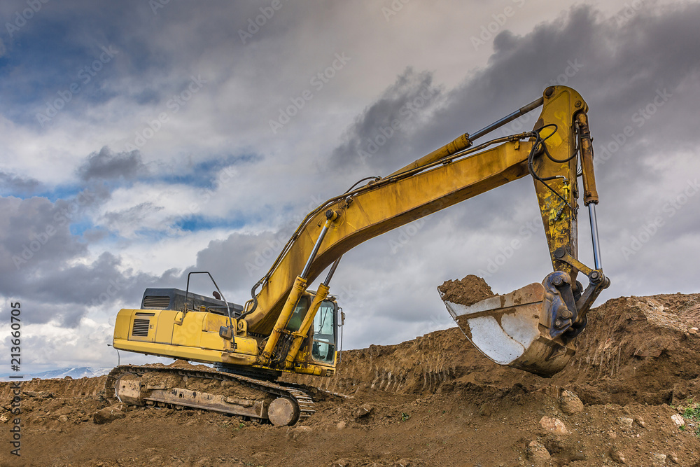 Excavator loading earth to perform works of settlement of a road Excavator loading earth to perform works of settlement of a road