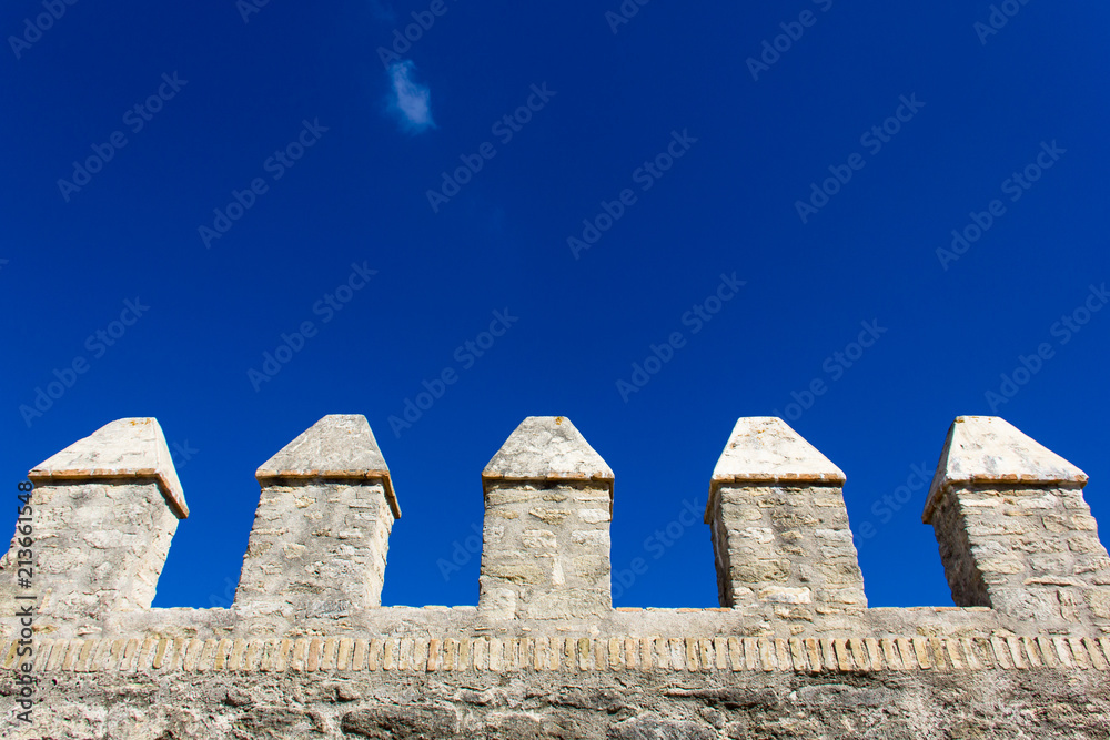 Moorish castle wall columns on intense blue sky in Vejer town, Andalusia. Medieval fortification, defense, protection concepts Moorish castle wall columns on intense blue sky in Vejer town, Andalusia. Medieval fortification, defense, protection concepts
