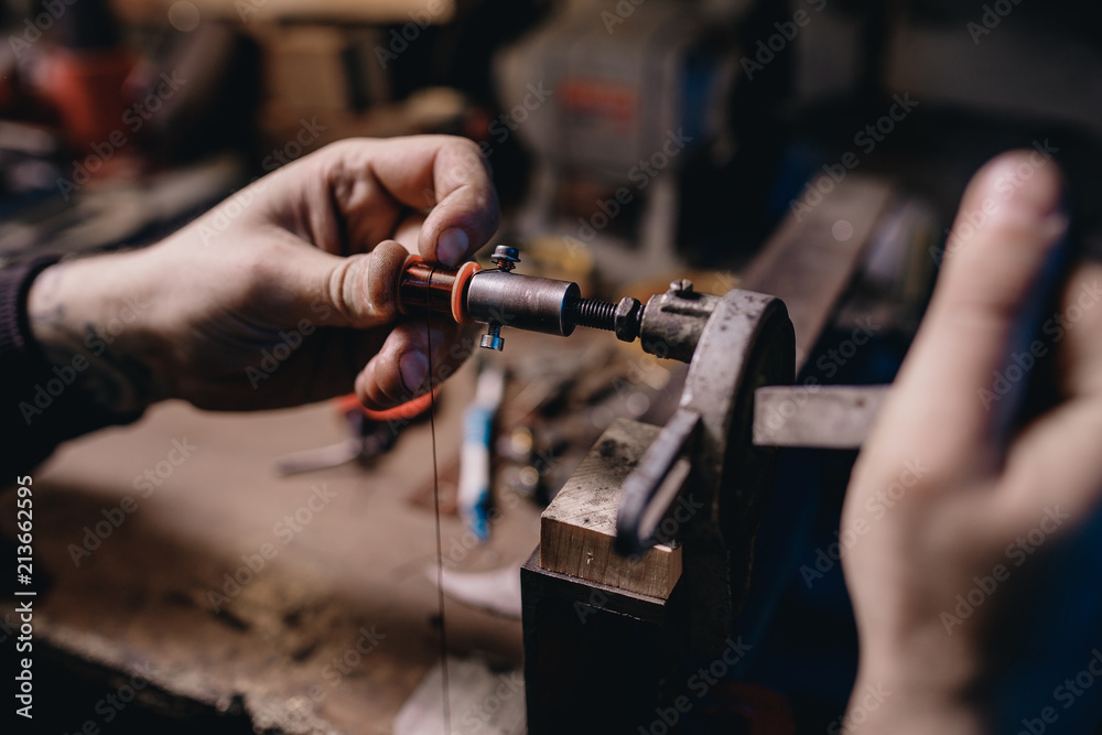 Man winds an induction coil made of copper wire for tattoo machines.