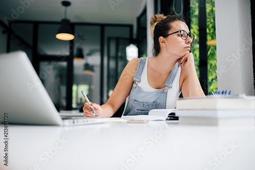 Procrastination concept. Girl looking away while studying. photo