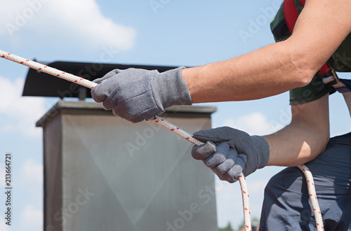 Mann nutzt Seilsicherung am Hausdach. Detailansicht