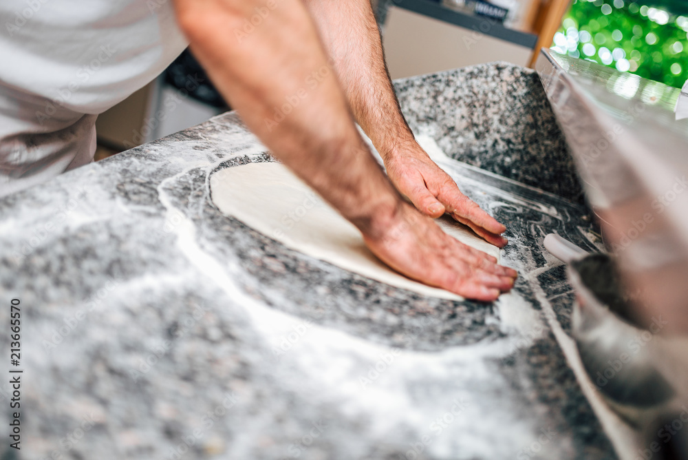 Chef preparing pizza dough.