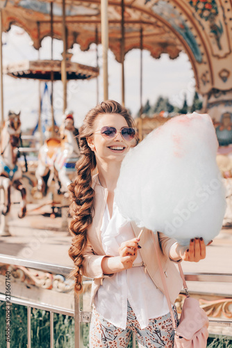 Portrait of a Smiling Beautiful Lady in Sunglasses Holding Cotton Candy at Park and Happily Looking in Camera.