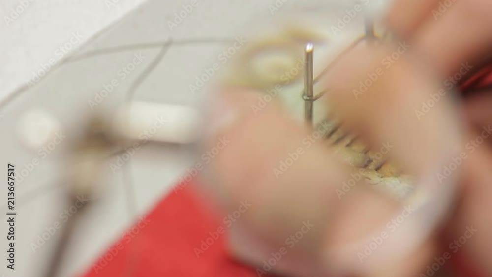 Close up of cable being tied up by pincers in hand, shot from magnifyng glass. Concept: people, engineering, handmade, profession, technic