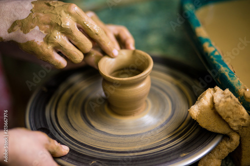 Sculpts in clay pot closeup. Modeling clay close-up. Caucasian man making vessel daytime of white clay in fast moving circle. Art, creativity. Ukraine, cultural traditions. Hobbies