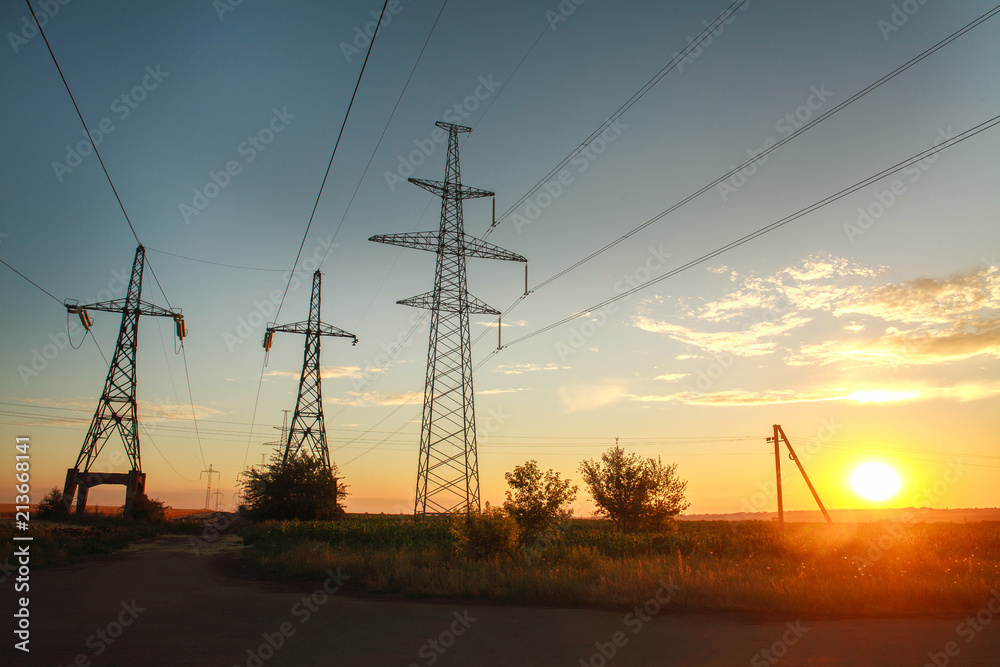 High electricity power line towers at dramatic sunset