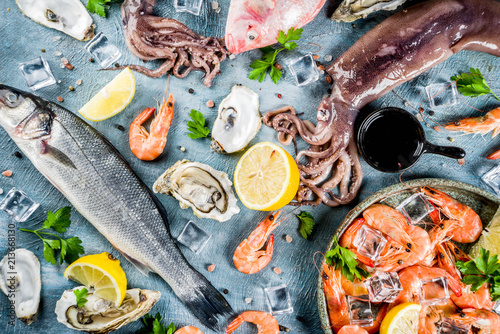 Fresh raw seafood squid shrimp oyster mussels fish with spices of herbs lemon on a light blue background copy space top view photo