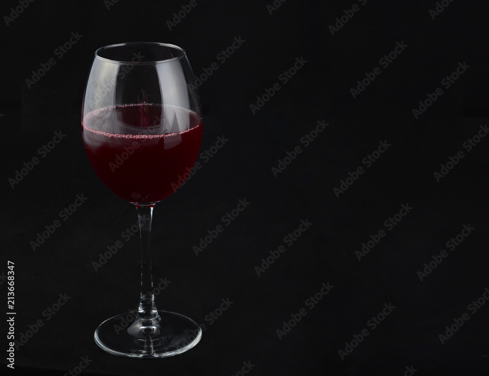 one transparent glass with a red drink on a black background one transparent glass with a red drink on a black background