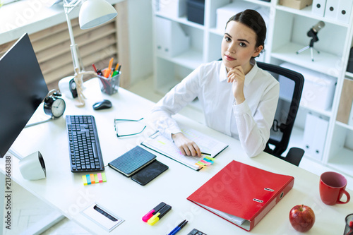 A young girl is sitting at the computer desk in the office. photo