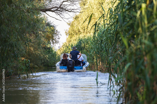 Tourists enjoying the Romanian beautiful Danube delta. Group of people on a boat trip in the Danube Delta Biosphere Reserve. Danube delta is the second largest river delta in Europe.