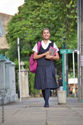 Female Student Wearing Uniform Walking On Sidewalk