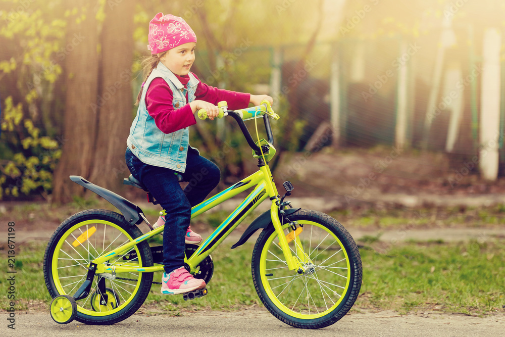 Beautiful smiling little girl riding bicycle in a park Beautiful smiling little girl riding bicycle in a park