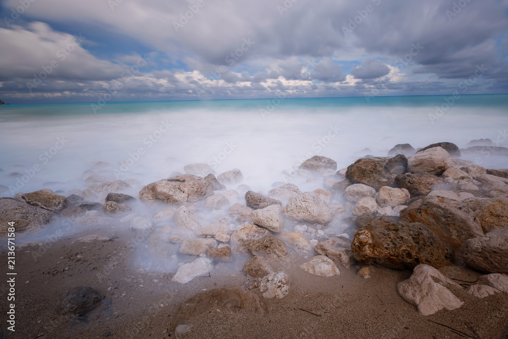 Incoming tides on a rocky beach under stormy skies, long exposure image 