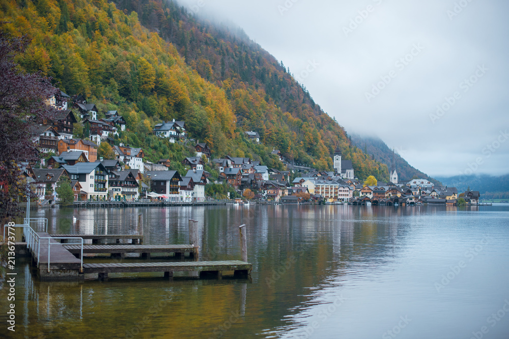 Beautiful autumn view of Hallstatt lake, mountains and village with houses and church in Austria. Foggy weather.