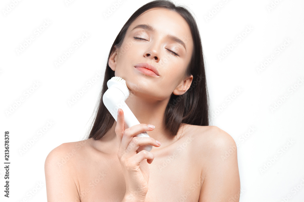 Young beautiful woman looks after skin with an exfoliating brush